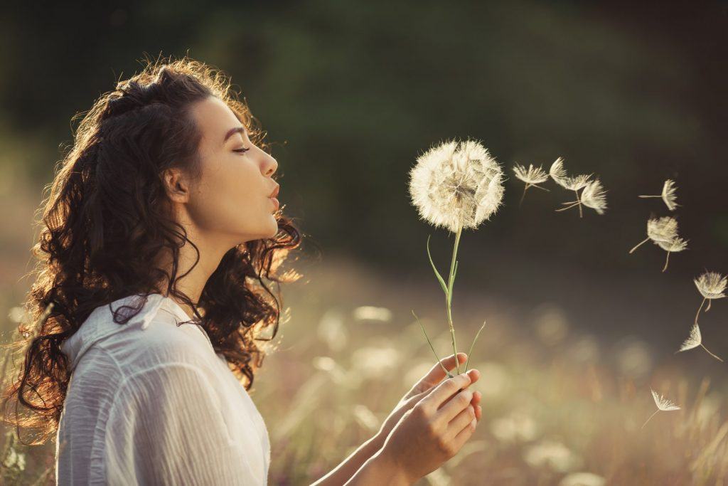 Woman Blowing Dandelion Into The Wind