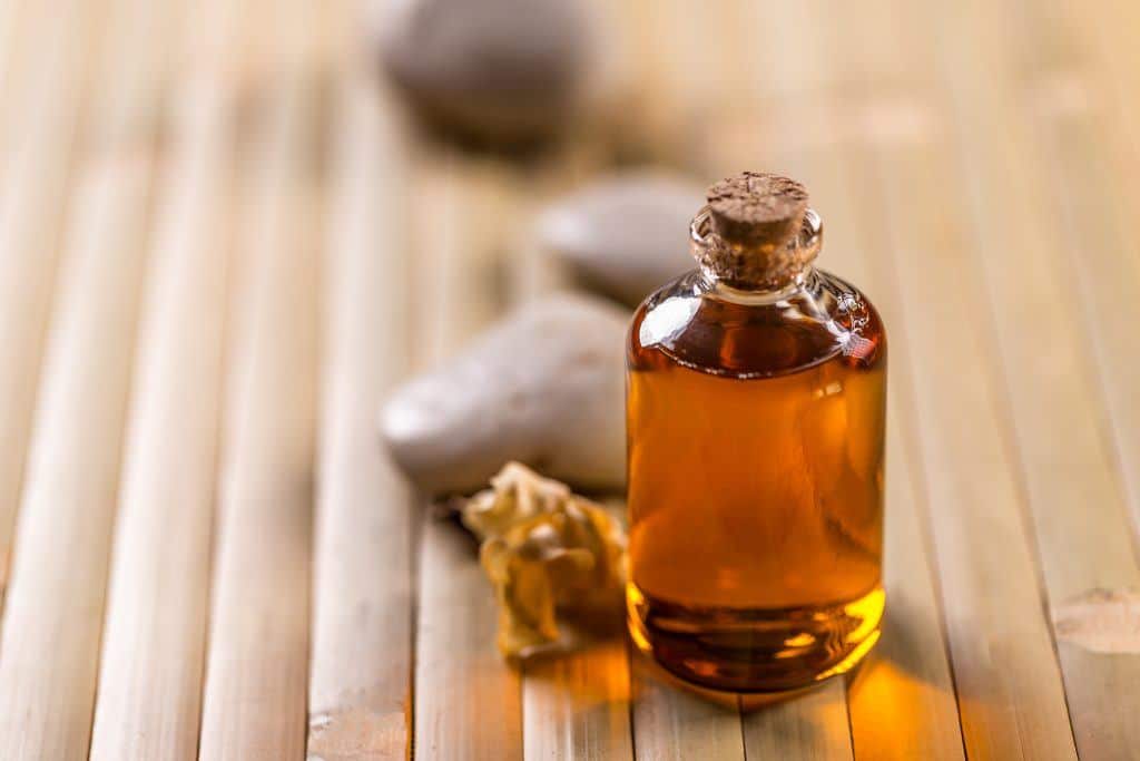 Bottle Of Essential Oil Standing On Wood