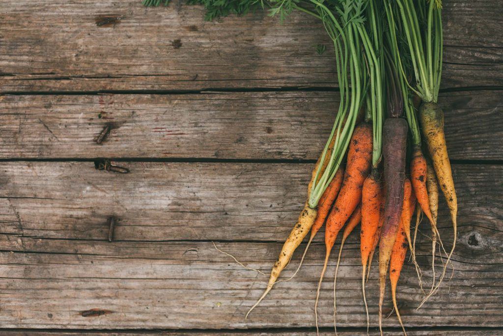 Bundle Of Carrots Laying On Wooden Backdrop