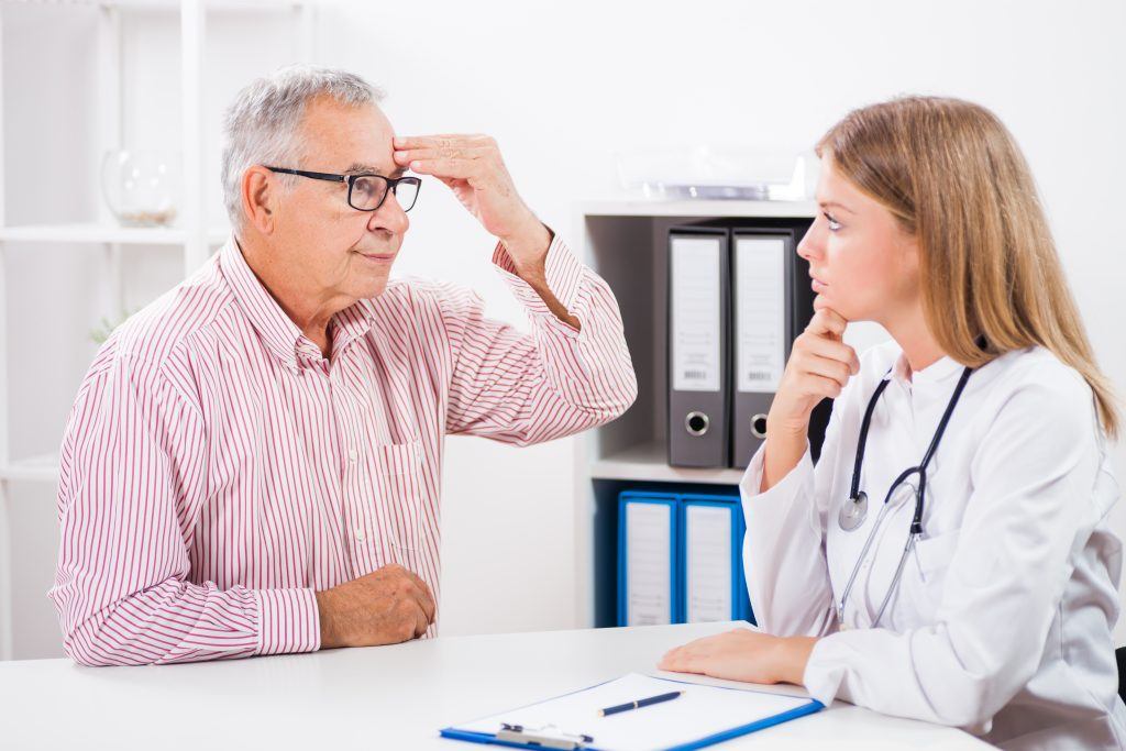 Doctor And Patient Conversing, Man Pointing To Headache